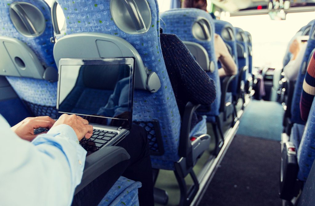 Guy on laptop inside company bus trip
